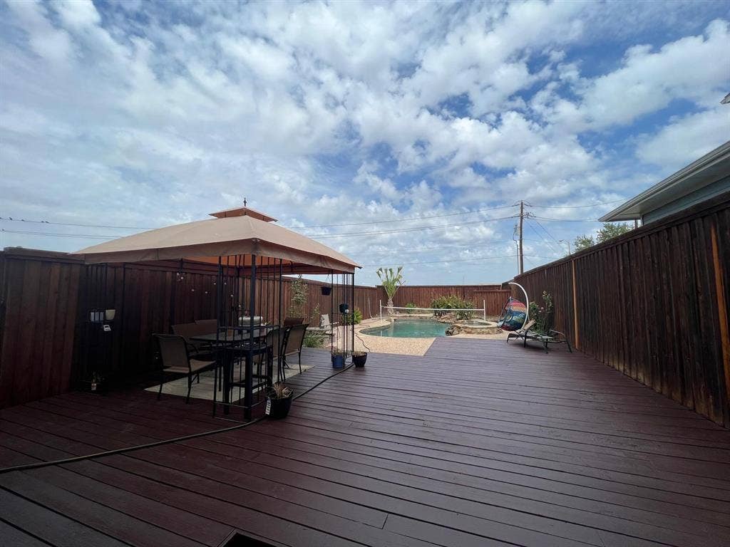 Spacious backyard featuring a large swimming pool, expansive wood deck, and a privacy fence