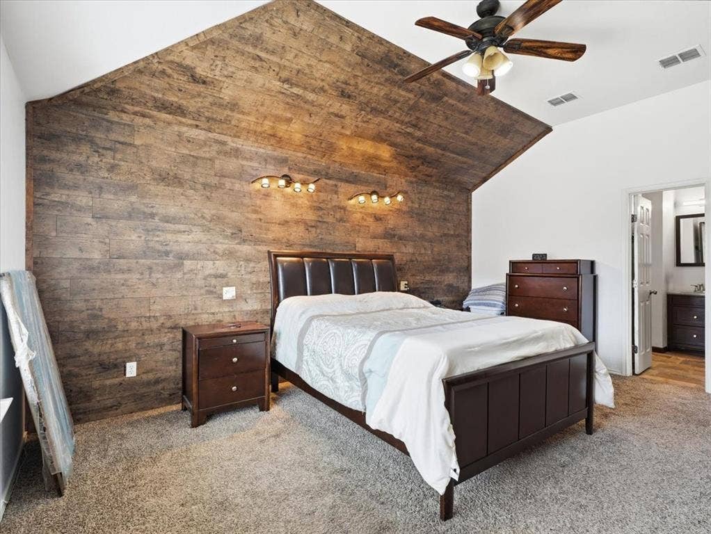 1039 Wood Brook Drive, Grand Prairie, TX 75052 Vaulted ceiling bedroom with accent wood-finish wall and mounted lighting