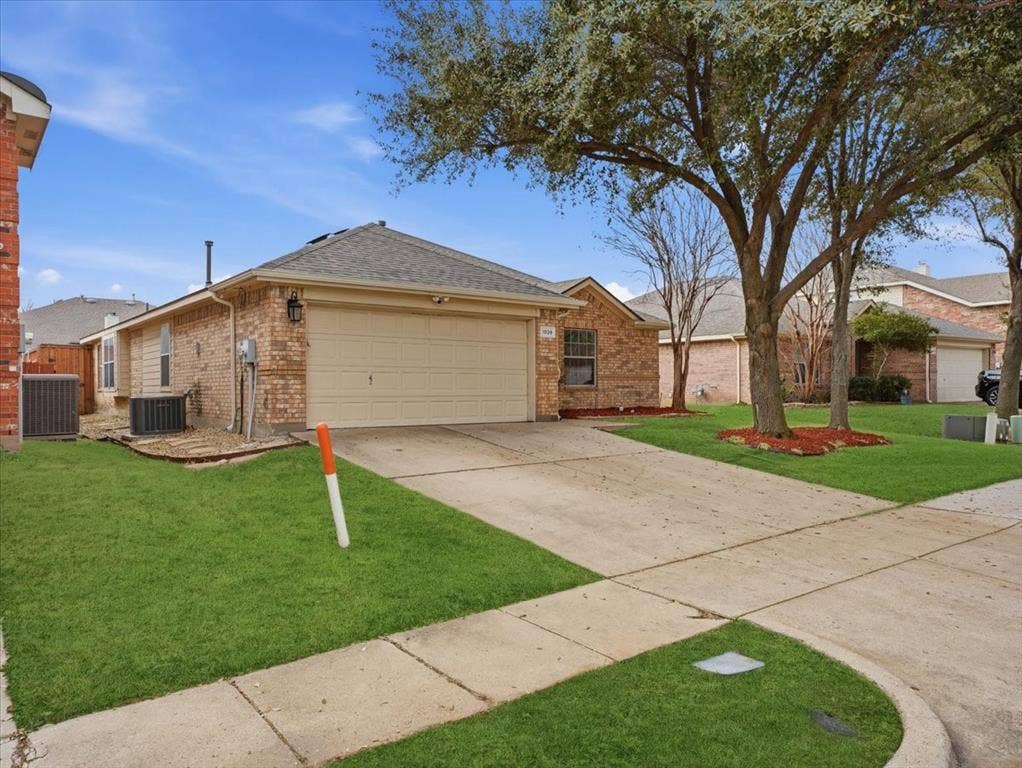 1039 Wood Brook Drive, Grand Prairie, TX 75052 Brick exterior with an attached garage and a concrete driveway