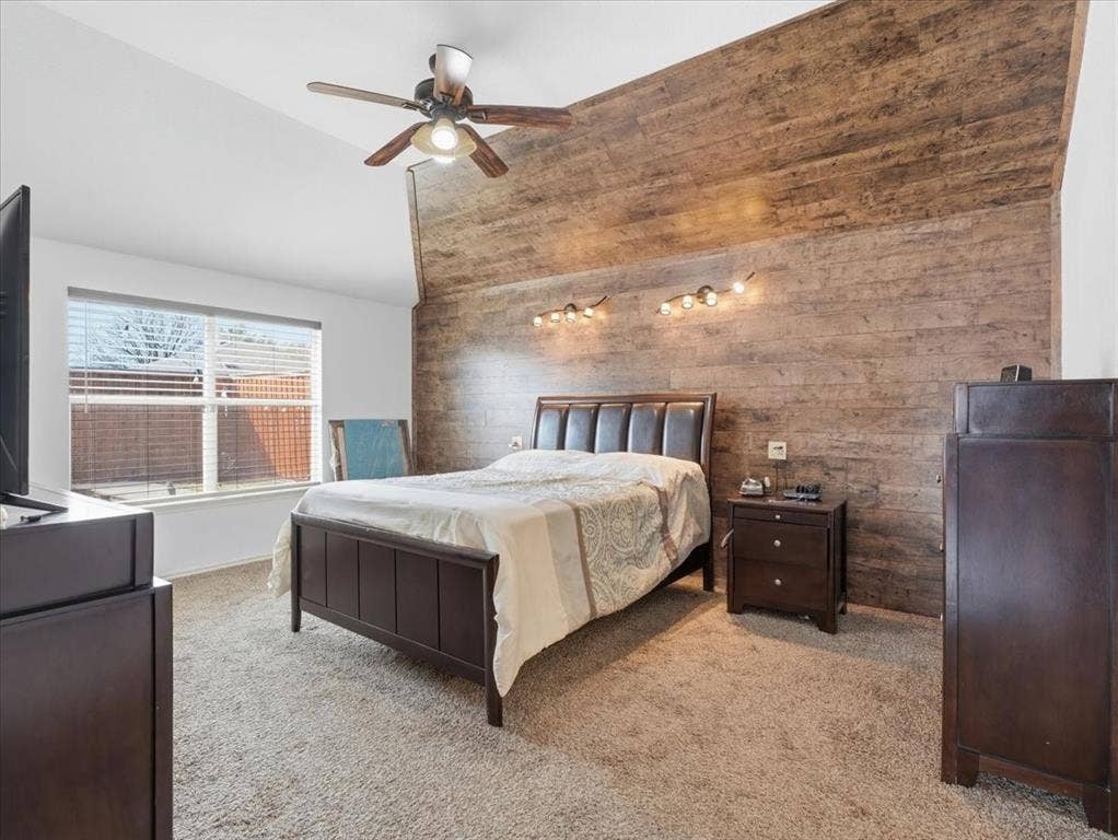1039 Wood Brook Drive, Grand Prairie, TX 75052 Bedroom featuring a sloped ceiling, wood-finish accent wall, and beige carpet