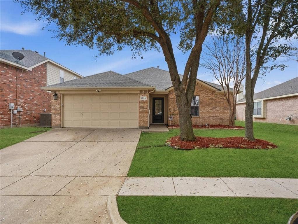 1039 Wood Brook Drive, Grand Prairie, TX 75052 Brick-clad single-story residence featuring an attached garage with a segmented door