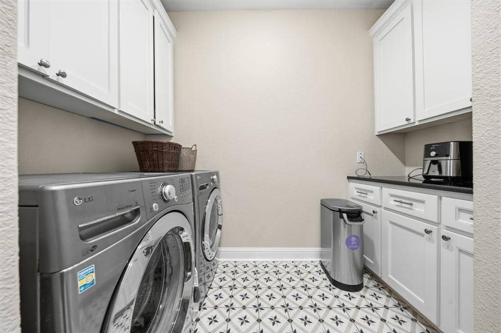 386 Cavitt Court, Robinson, TX 76706 Laundry room featuring patterned floor tile, white shaker-style cabinetry, and dark countertops