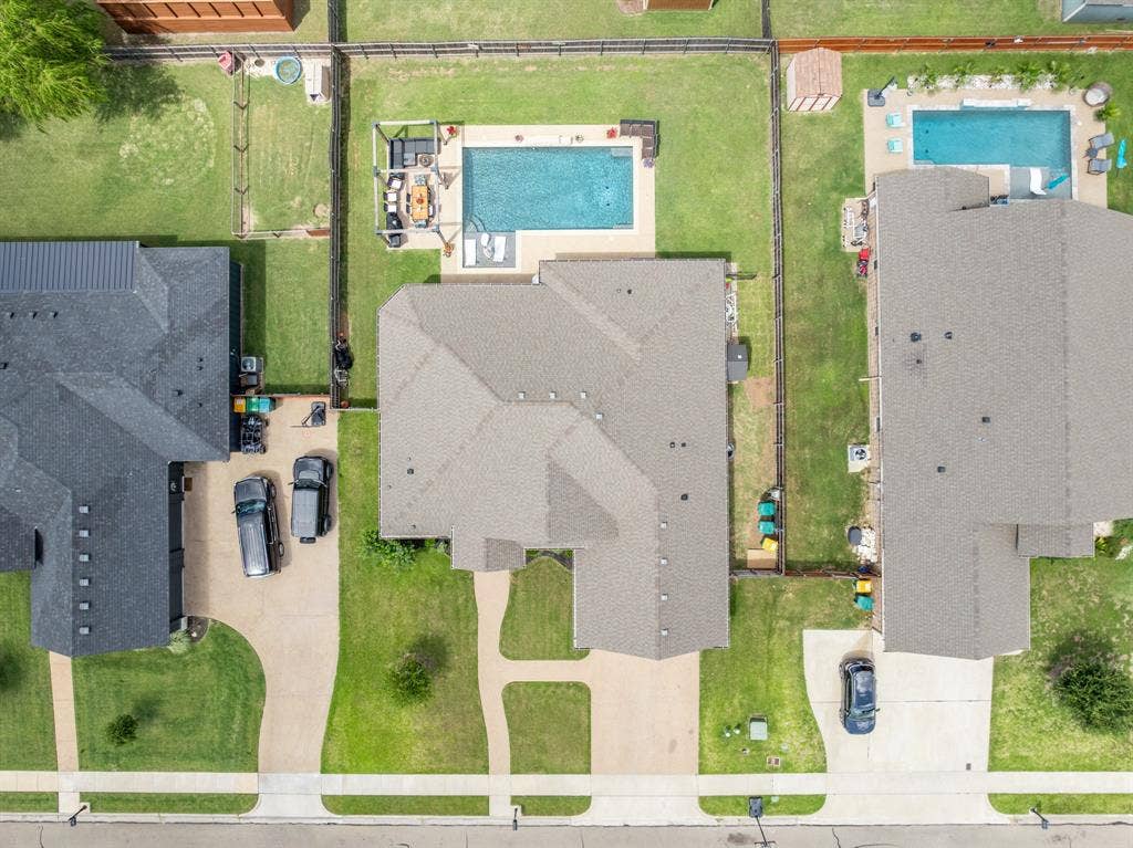 386 Cavitt Court, Robinson, TX 76706 Expansive property featuring a rectangular pool with surrounding concrete decking, a substantial main residence with an asphalt shingle roof, and a paved driveway