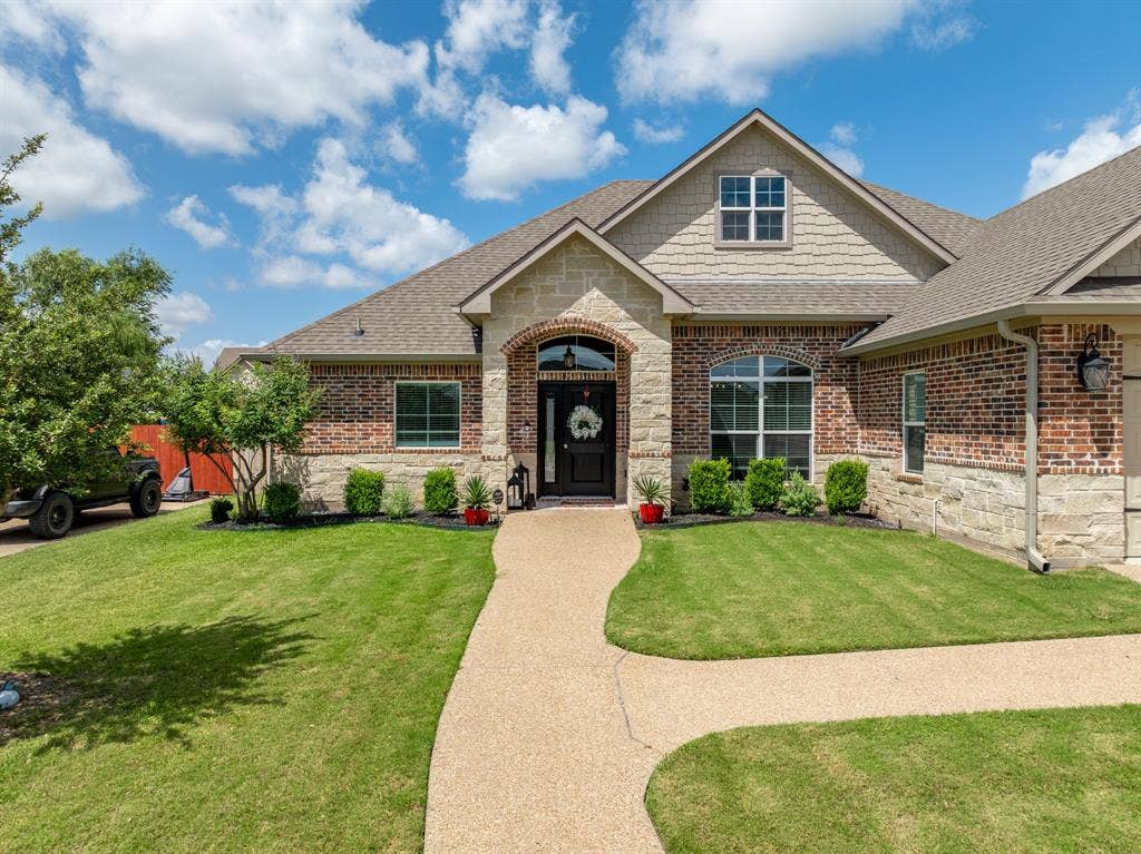 386 Cavitt Court, Robinson, TX 76706 Traditional-style residence featuring a combination brick and stone facade, an arched entry, and a gabled roofline