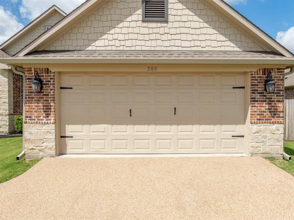 386 Cavitt Court, Robinson, TX 76706 Front exterior featuring a multi-tone brick and stone facade, shake siding, an integrated garage with decorative hardware, and a textured aggregate driveway