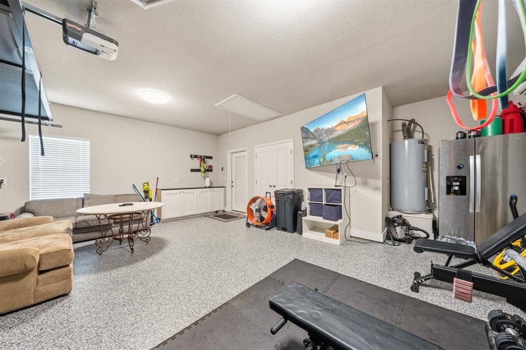 386 Cavitt Court, Robinson, TX 76706 Spacious garage with light gray speckled epoxy flooring, white built-in cabinetry with a dark countertop, overhead garage door opener, and a single window with blinds