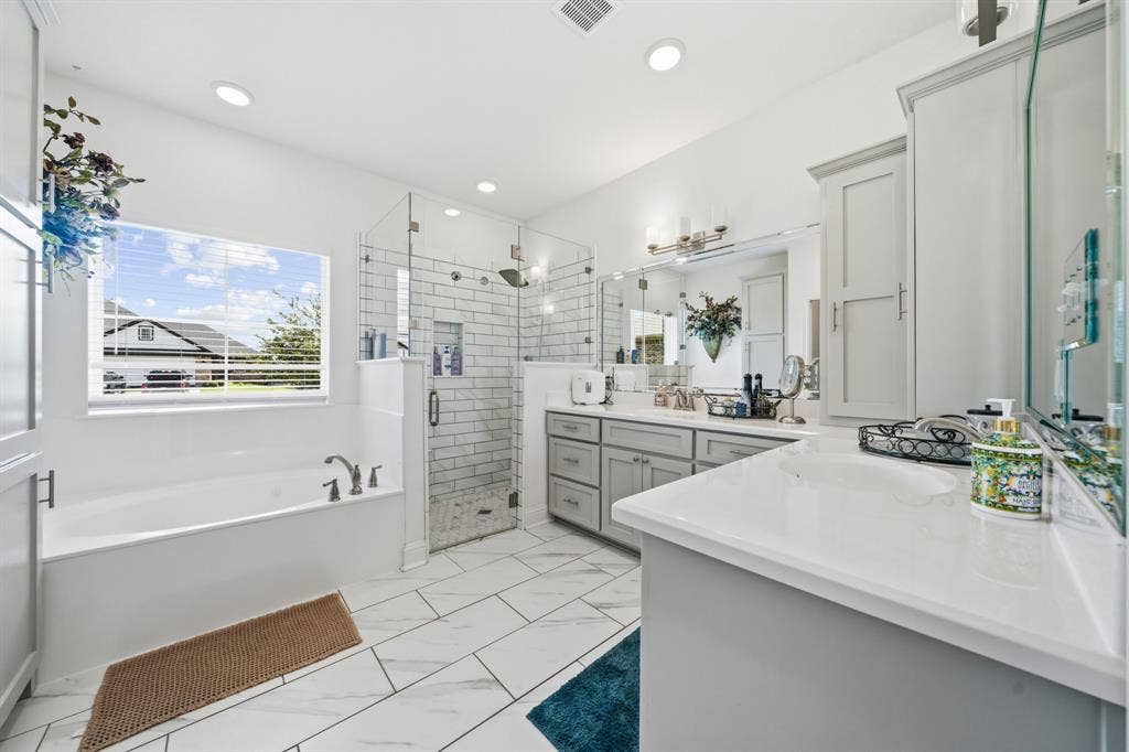 386 Cavitt Court, Robinson, TX 76706 Bathroom featuring a built-in bathtub, a walk-in shower with subway tile, a dual vanity with light gray cabinetry and white countertops, and white tile flooring