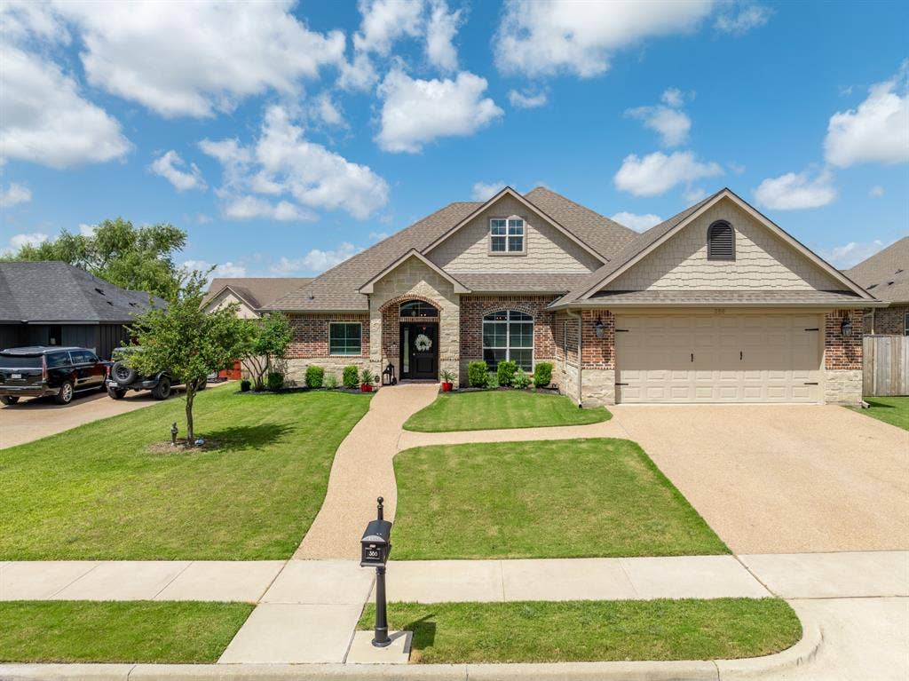 386 Cavitt Court, Robinson, TX 76706 Single-story residence featuring a brick and stone exterior, a gabled roofline, an attached two-car garage, a concrete driveway, and a curved pebble pathway leading to the front entry