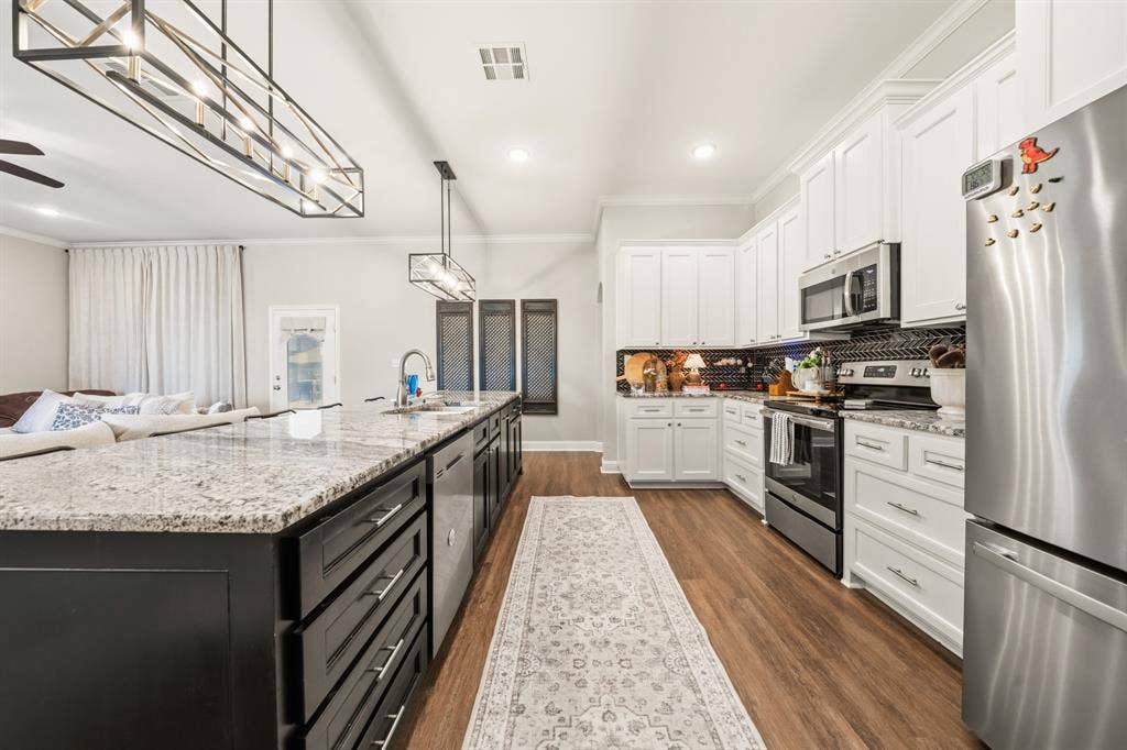 386 Cavitt Court, Robinson, TX 76706 Modern kitchen featuring a large island with stone countertop, white shaker cabinetry, stainless steel appliances, and wood-finish flooring