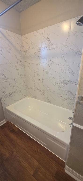 235 Vista Way, Benbrook, TX 76126 White soaking tub with a wall-mounted showerhead, surrounded by white tile with grey veining, and wood-finish flooring