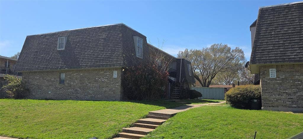 235 Vista Way, Benbrook, TX 76126 Brick exterior building featuring a mansard roof with dormer windows, a walkway with steps, and a grassy front yard