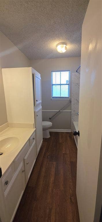 235 Vista Way, Benbrook, TX 76126 Wood-finish flooring, white vanity with integrated sink, white storage cabinetry, white toilet, and a tiled shower-tub combination