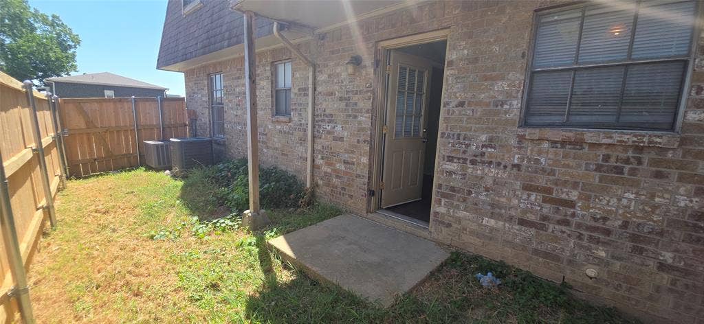235 Vista Way, Benbrook, TX 76126 Spacious backyard featuring mature landscaping and a fenced perimeter, with direct access via concrete patio and sliding glass door entry