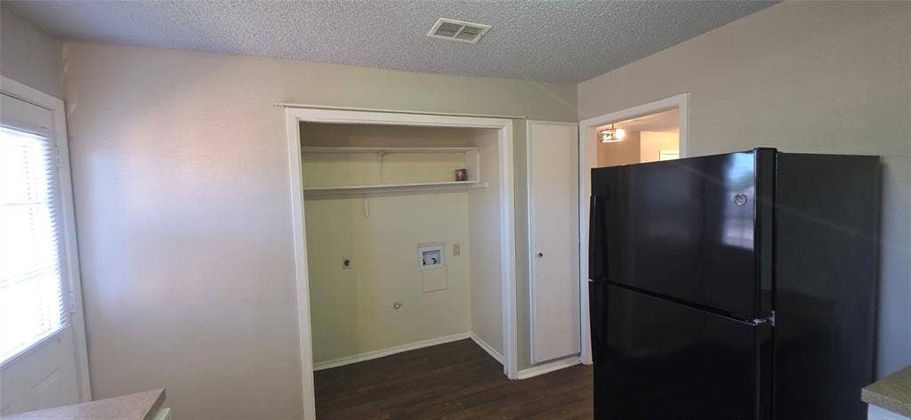 235 Vista Way, Benbrook, TX 76126 Built-in laundry closet with shelving, wood-finish flooring, and a black refrigerator