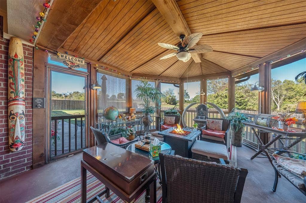 126 E Post Oak, Frankston, TX 75763 Enclosed patio featuring a wood-paneled vaulted ceiling, brick accent wall, ceiling fan, and built-in fire pit