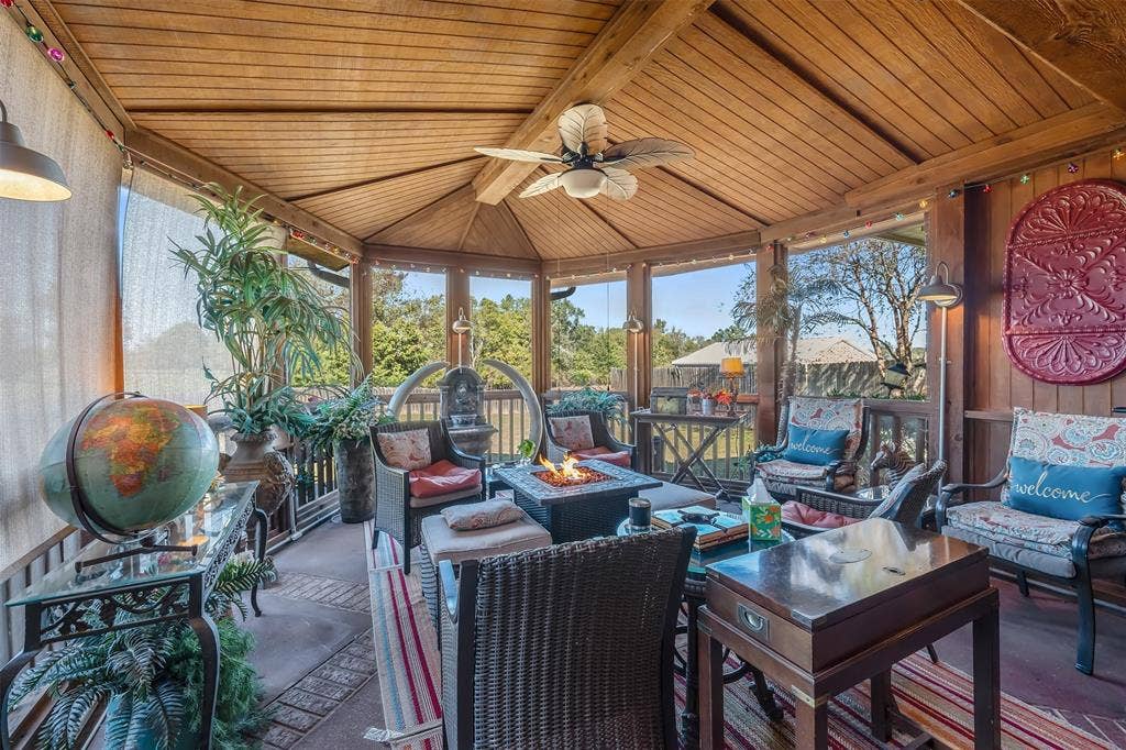 126 E Post Oak, Frankston, TX 75763 Screened porch featuring a wood-plank vaulted ceiling, ceiling fan, multiple windows, and a built-in fire pit
