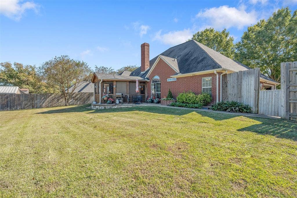 126 E Post Oak, Frankston, TX 75763 Expansive fenced backyard featuring a screened porch with a stone base, brick exterior, and a prominent chimney