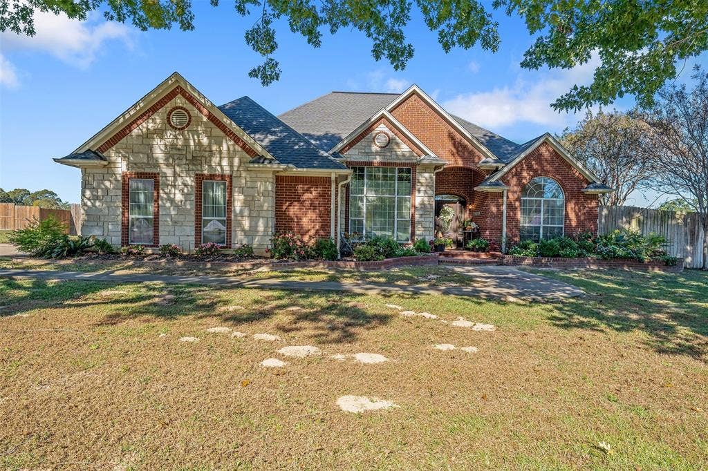 126 E Post Oak, Frankston, TX 75763 Brick and stone facade residence featuring a prominent front entrance, multiple gables, an arched window, and a large bay window