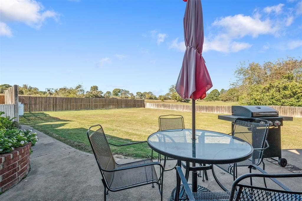 126 E Post Oak, Frankston, TX 75763 Expansive backyard featuring a concrete patio, mature trees, and a wood privacy fence