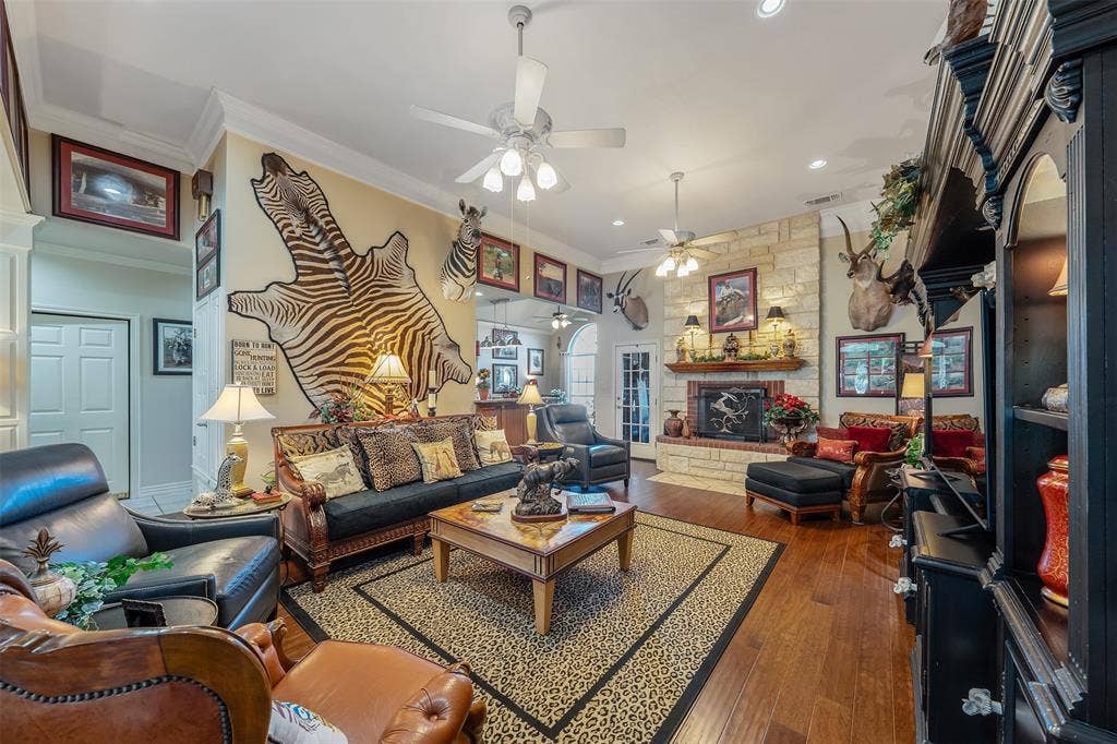 126 E Post Oak, Frankston, TX 75763 Spacious room featuring wood-finish flooring, a stone-clad fireplace with a brick firebox, and multiple ceiling fans
