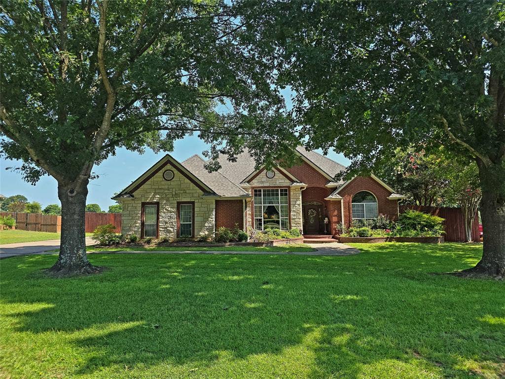 126 E Post Oak, Frankston, TX 75763 Brick and stone exterior residence featuring a gabled roofline and an arched entryway