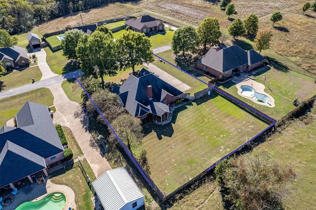 126 E Post Oak, Frankston, TX 75763 Expansive property featuring a large grass lawn, mature trees, an in-ground swimming pool, and a brick-faced residence with a gabled roof