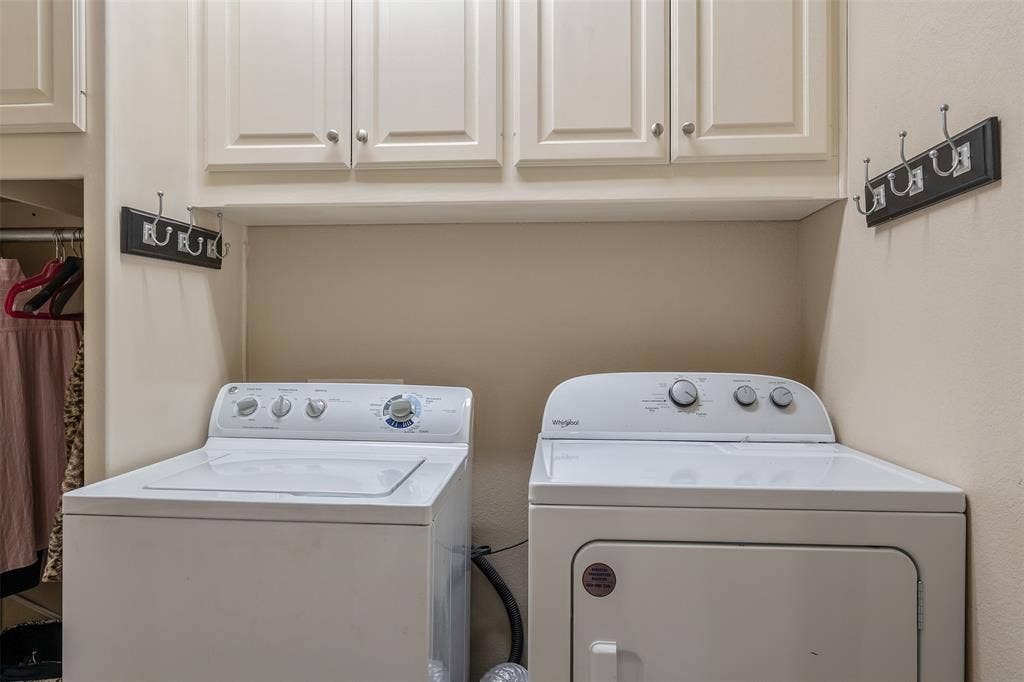 126 E Post Oak, Frankston, TX 75763 Laundry area featuring upper cabinetry with panel doors and brushed nickel hardware, neutral wall paint, and a built-in hanging rod in the adjacent alcove