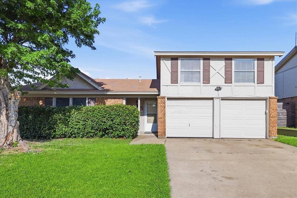 6505 Hughes Drive, Watauga, TX 76148 Two-story exterior with a two-car garage, white siding, and brick accents