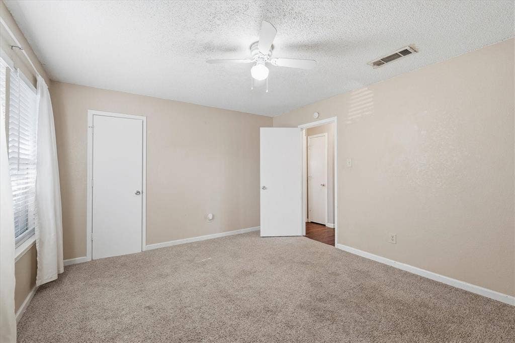 6505 Hughes Drive, Watauga, TX 76148 Carpeted interior room featuring light beige walls and a window with white blinds and curtains
