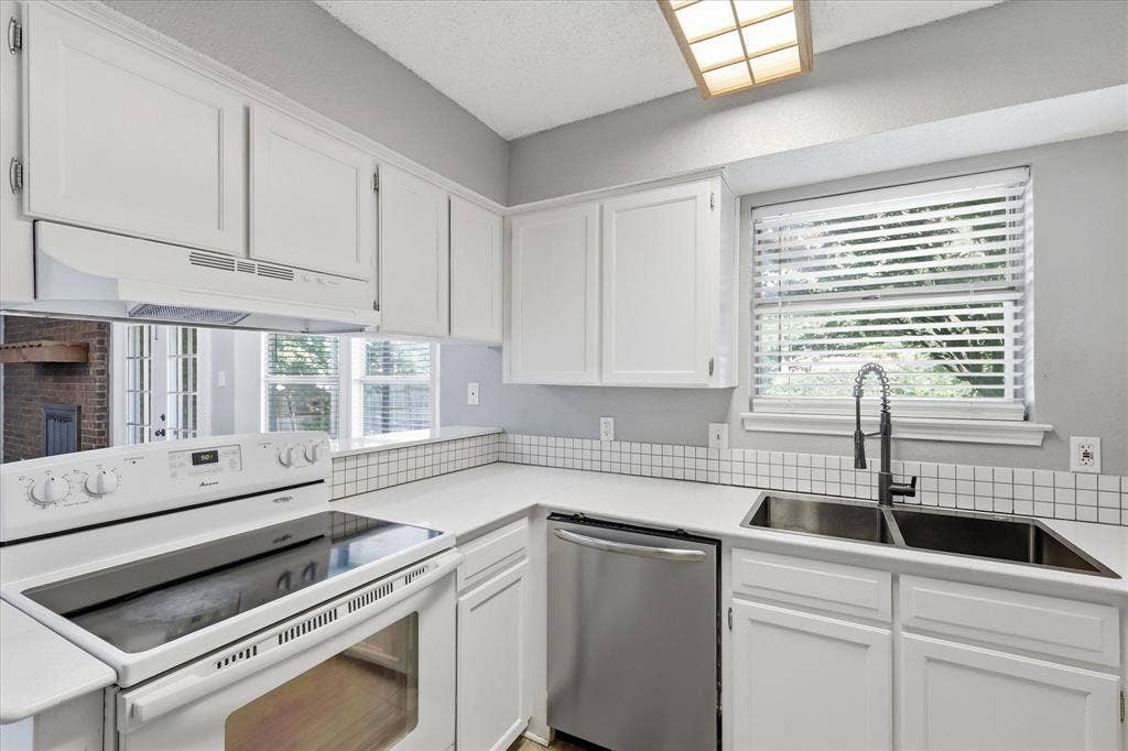 6505 Hughes Drive, Watauga, TX 76148 Kitchen featuring white cabinetry, solid surface countertops, a white electric range, and a stainless steel double basin sink with a gooseneck faucet