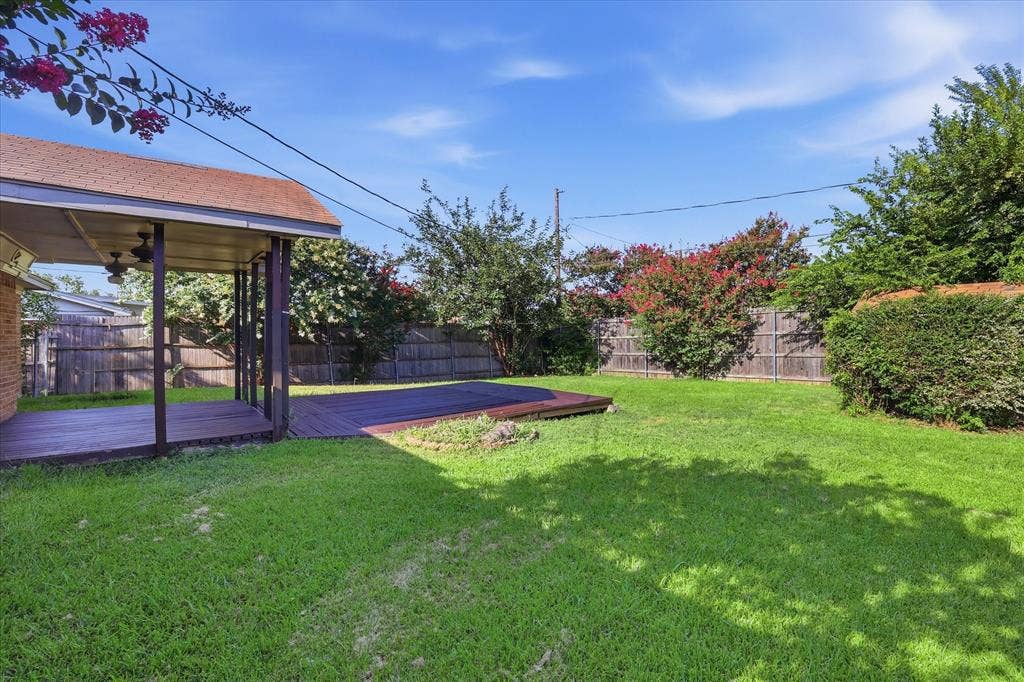 6505 Hughes Drive, Watauga, TX 76148 Expansive backyard featuring a large covered patio with ceiling fans, an additional open deck area, and a privacy fence