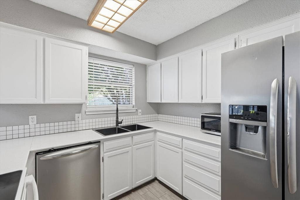6505 Hughes Drive, Watauga, TX 76148 Kitchen featuring white cabinetry, white countertops, square tile backsplash, and stainless steel appliances including a double-door refrigerator and dishwasher