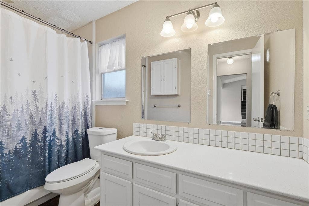6505 Hughes Drive, Watauga, TX 76148 Bathroom featuring a single basin vanity with white cabinetry, a built-in medicine cabinet, and a three-light vanity fixture