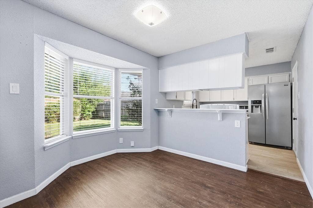 6505 Hughes Drive, Watauga, TX 76148 Bay window with horizontal blinds and wood-finish flooring