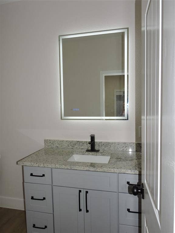 163 Lake Creek Drive, Mabank, TX 75156 Bathroom vanity featuring light-toned cabinetry with black hardware, a light-speckled countertop, a rectangular undermount sink, and a matte black faucet