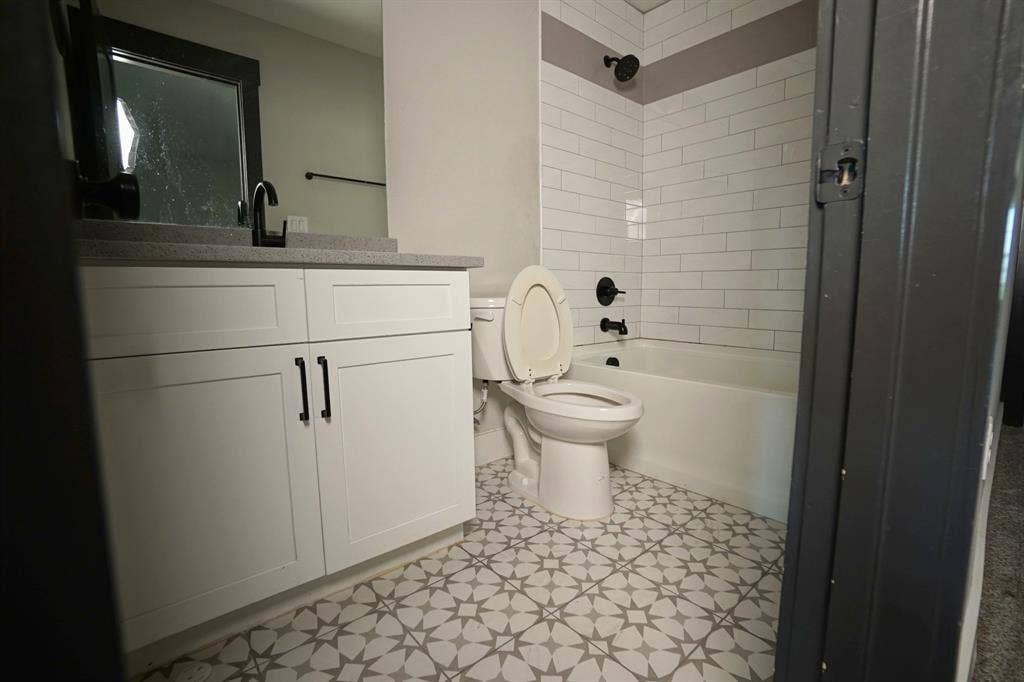 1764 Palladio Loop, Princeton, TX 75407 Modern bathroom featuring decorative floor tiles, a white vanity with dark hardware, a coordinated dark faucet, and subway tile shower surround