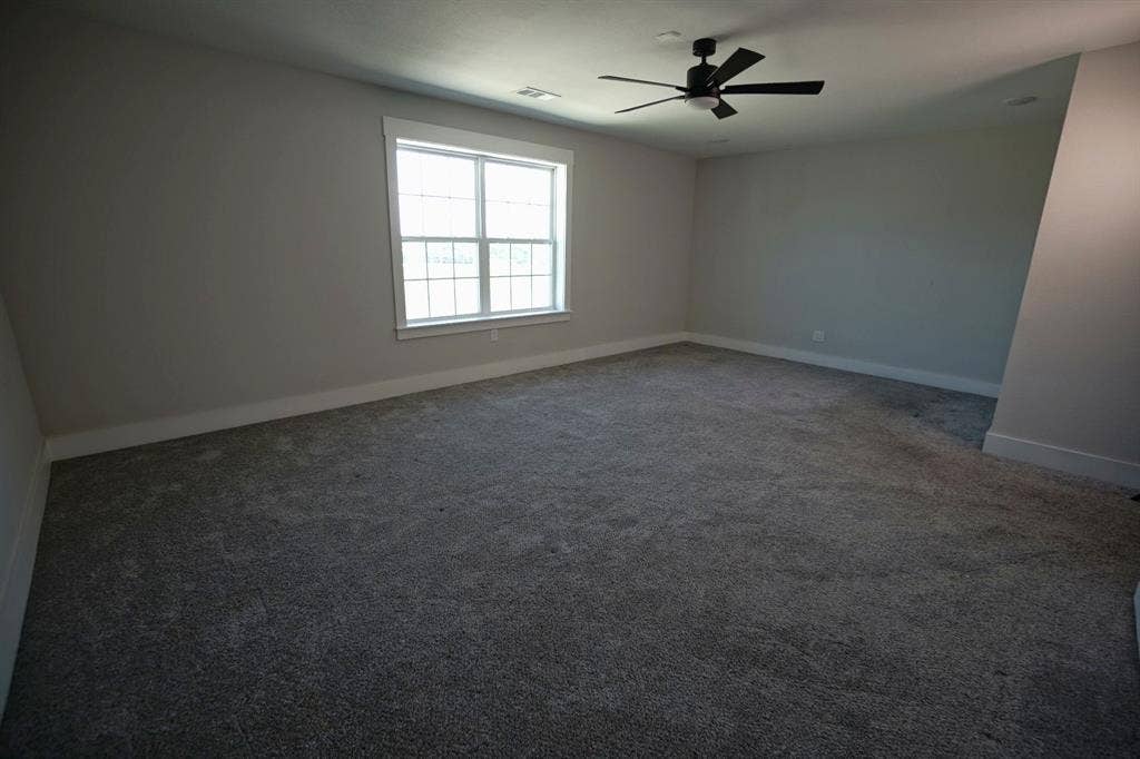 1764 Palladio Loop, Princeton, TX 75407 Spacious room with gray textured carpeting, a multi-pane window, and a ceiling fan with integrated lighting
