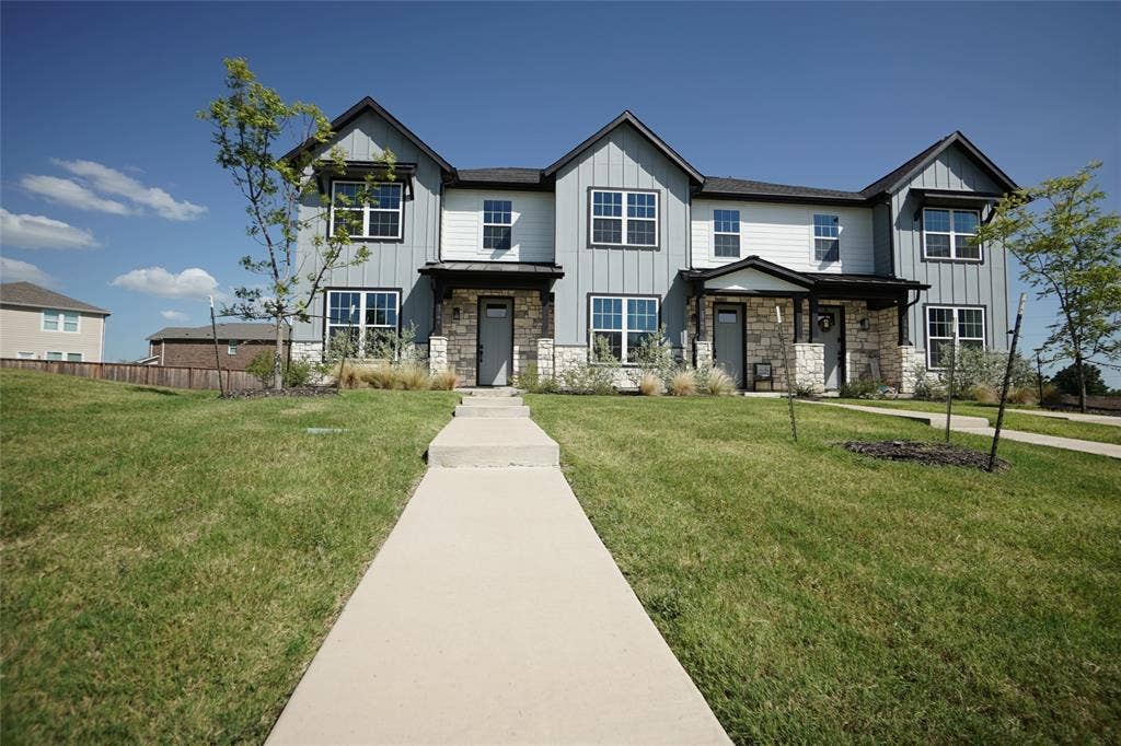 1764 Palladio Loop, Princeton, TX 75407 Modern townhome exterior with stone accents, vertical and horizontal siding, multiple windows, and a covered entry