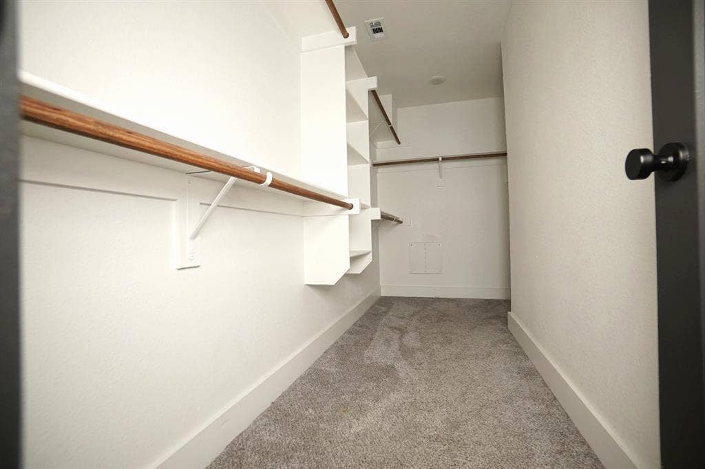 1764 Palladio Loop, Princeton, TX 75407 Walk-in closet with built-in shelving, wood-finish hanging rods, and gray carpeting