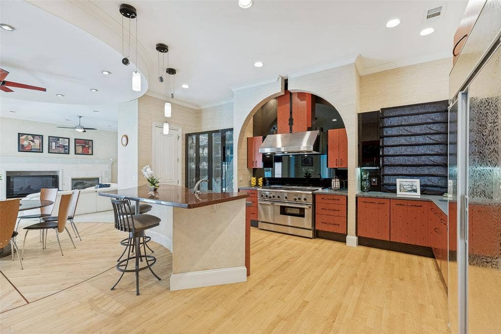 5920 Mcfarland Drive, Plano, TX 75093 Open-concept kitchen featuring wood-finish flooring, a stainless steel range with a professional hood, and a built-in refrigerator with a frosted glass door