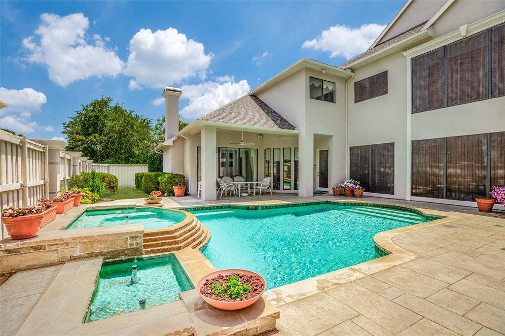 5920 Mcfarland Drive, Plano, TX 75093 Expansive outdoor living area featuring a large swimming pool with integrated spa, a tiered water feature, and a covered patio
