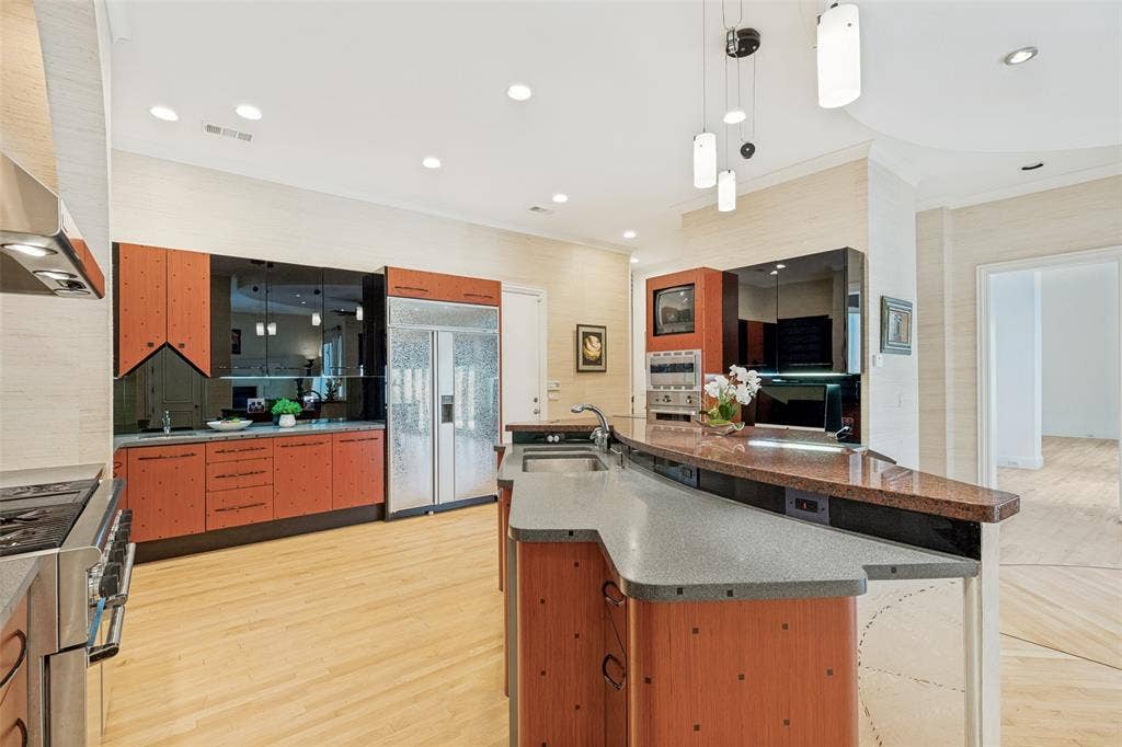 5920 Mcfarland Drive, Plano, TX 75093 Kitchen featuring wood-finish cabinetry, stainless steel appliances, recessed lighting, and a multi-level island with a built-in sink and countertop seating