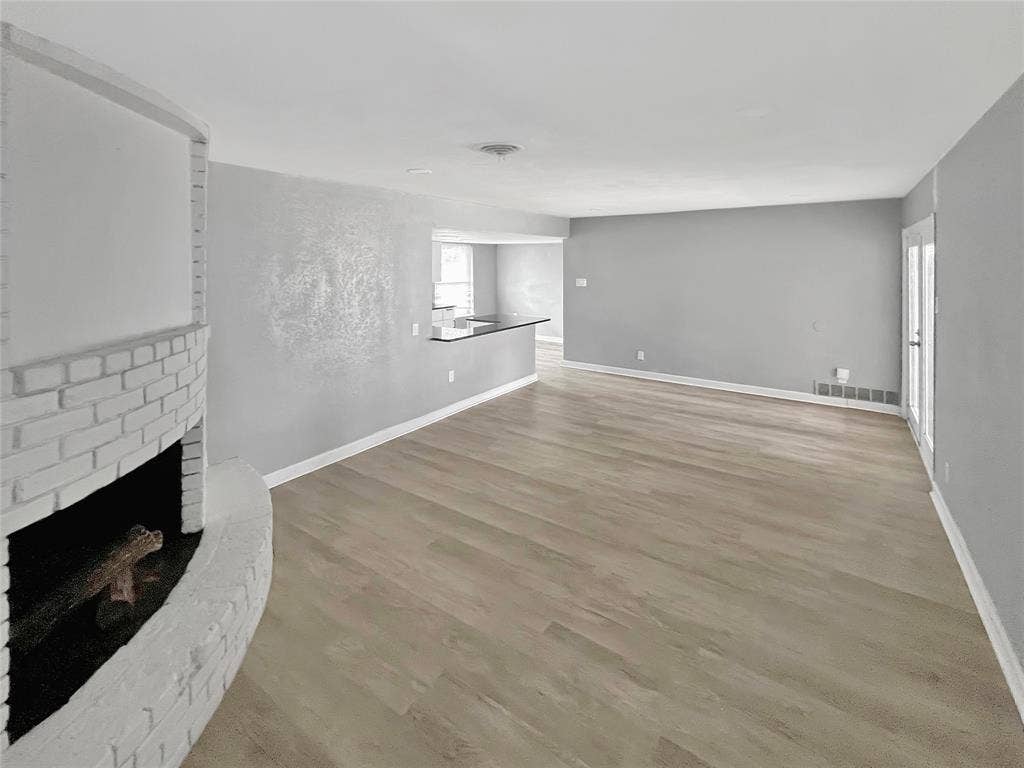 1306 Elby Street, Irving, TX 75061 Spacious living area featuring a curved brick fireplace, wood-finish flooring, and a contemporary color palette