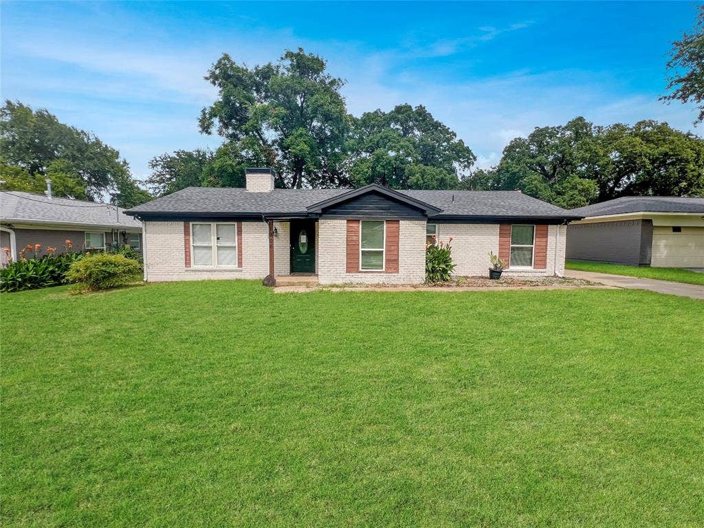 1306 Elby Street, Irving, TX 75061 Ranch-style exterior with a light-colored brick facade, dark roofing, and a prominent chimney
