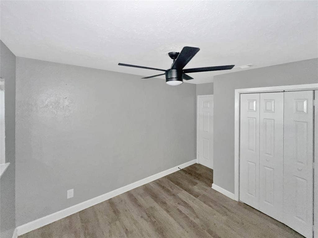 1306 Elby Street, Irving, TX 75061 Room featuring wood-finish flooring, light grey painted walls, white baseboards, and a contemporary black ceiling fan with integrated lighting