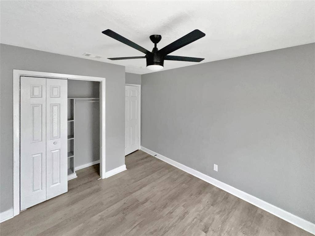 1306 Elby Street, Irving, TX 75061 Room featuring light gray walls, wood-finish flooring, and a contemporary black ceiling fan with integrated lighting