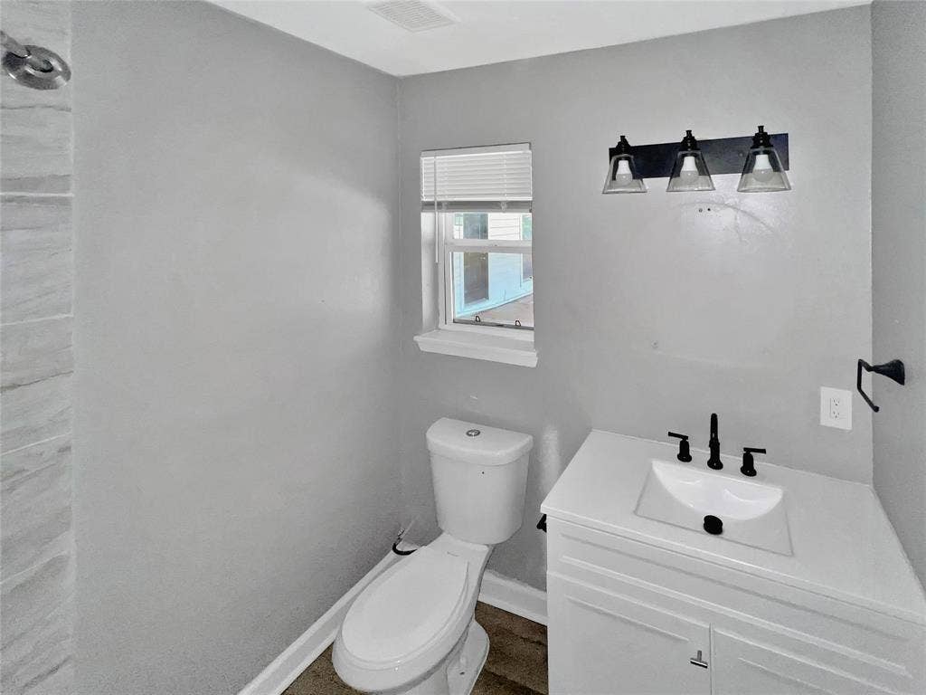 1306 Elby Street, Irving, TX 75061 Contemporary bathroom featuring a white vanity with integrated sink, black fixtures, and a three-light vanity bar