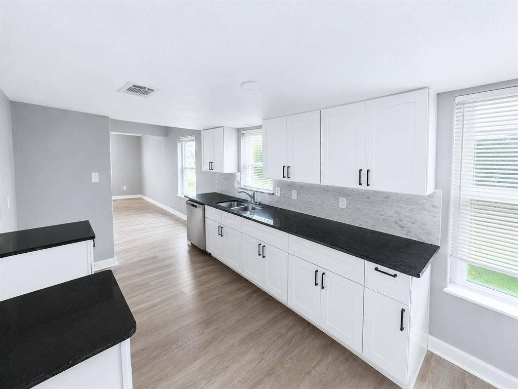1306 Elby Street, Irving, TX 75061 Kitchen featuring white shaker-style cabinetry with black hardware, dark countertops, and a light-toned tile backsplash