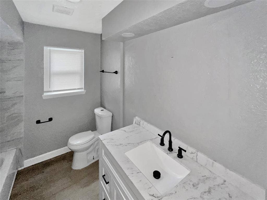 1306 Elby Street, Irving, TX 75061 Bathroom featuring a modern vanity with a marble-finish countertop, undermount sink, and matte black faucet