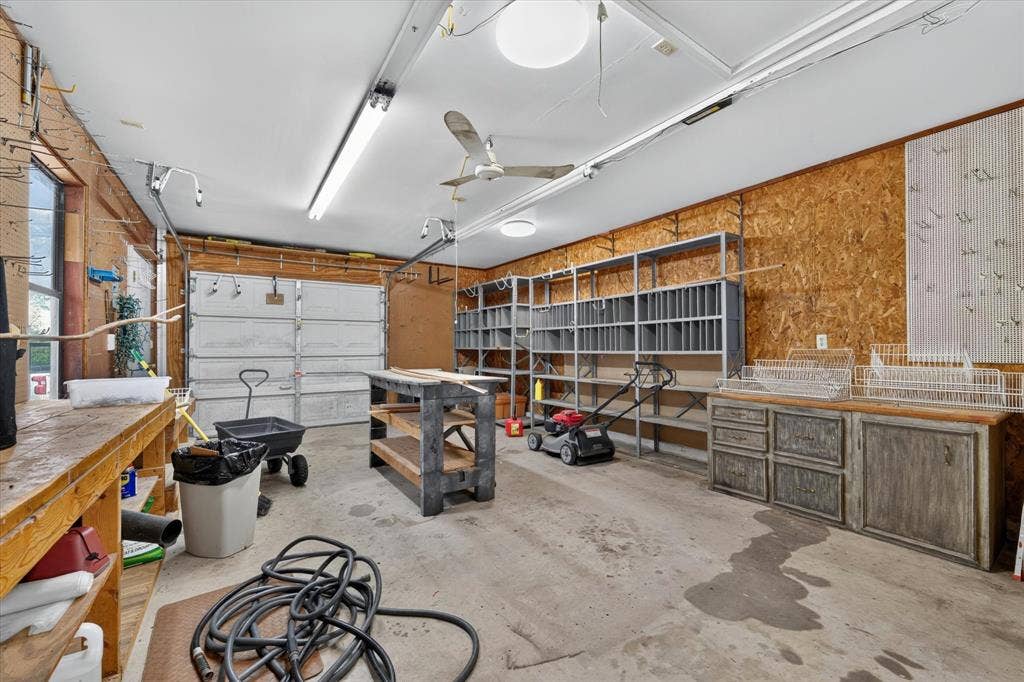 9700 Brookwood Circle, Woodway, TX 76712 Spacious garage featuring a concrete floor, multiple built-in shelving units, a workbench, and integrated overhead lighting